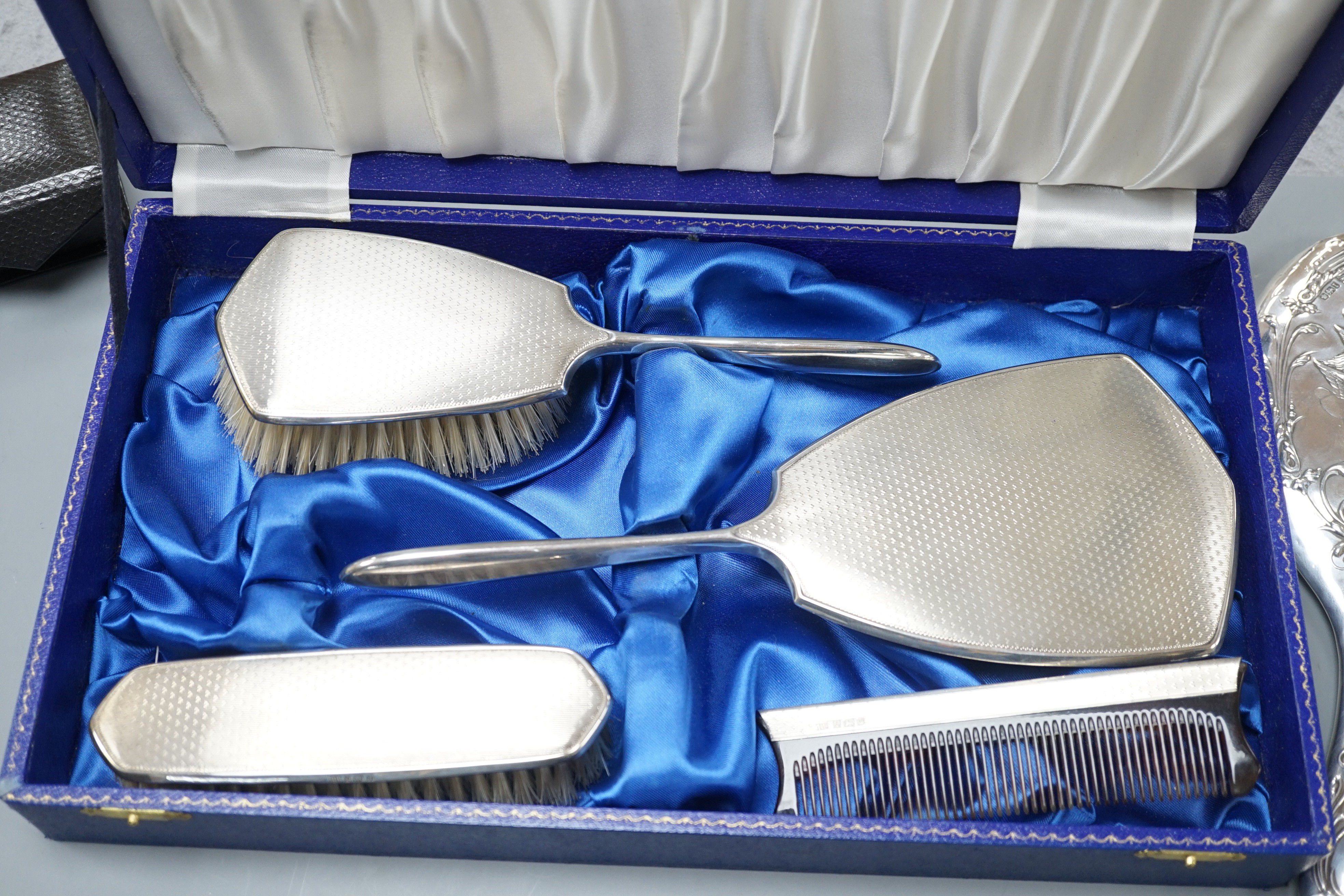 A cae 1970's engine turned silver mounted four piece mirror and brush set, two silver mounted hand mirrors and two silver mounted brushes.